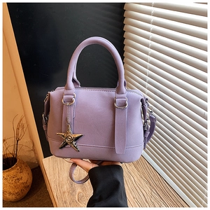 Detailed macro view of lavender purple matte leather pillow bag with metal star charm and handles