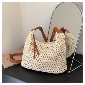 Dettaglio della borsa tote in maglia color crema con manici in pelle marrone e nappa