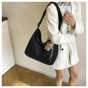 Detail of black large tote bag with cute brown teddy bear charm and soft satin finish