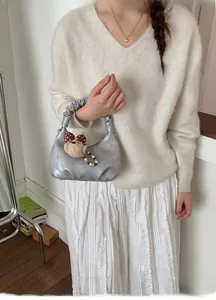 Detail of silver metallic hobo bag with scrunchie handle and cute plush bear charm
