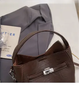 Detail of deep brown pebble grain leather bucket bag with silver twist lock and round handle