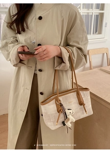 Détail d'un cabas en toile avec lanières en cuir marron et pendentif au style rétro