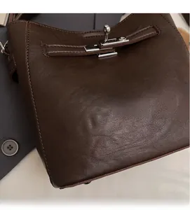 Close-up of dark brown leather bucket bag showing silver lock and stitching detail