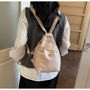 Nahaufnahme eines kompakten beigen Oxford-Rucksacks mit mehreren Lagen, von Model getragen
