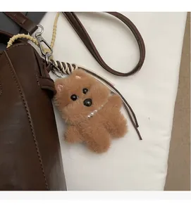 Detail of brown plush dog charm with pearl necklace and bone tag on leather handbag