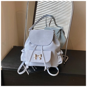 Detail of light blue faux leather backpack with gold bow and drawstring closure