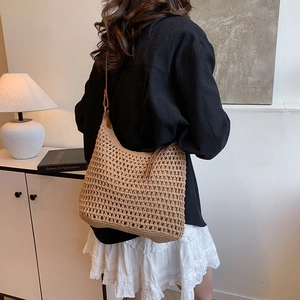 Dettaglio della trama in paglia intrecciata e tracolla in pelle marrone della borsa tote