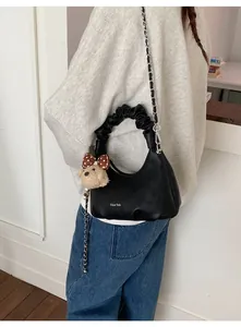 Detail of black leather crescent bag with scrunchie handle and plush bear charm