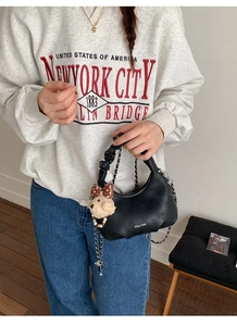 Detail of black pleated cloud bag with silver chain, logo print and plush bear charm