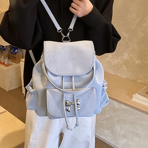 Detail of light blue suede backpack featuring a decorative metal bow and side pleats