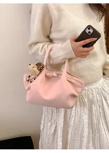 Detalle de bolso tote rosa claro con colgante de oso, hebilla ajustable y textura suave