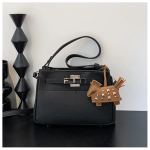 Detalle de bolso de cuero negro con cierre plateado y adorno de caballo con remaches