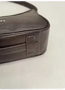 Macro shot of dark brown leather tote bag with contrast stitching and metal logo detail