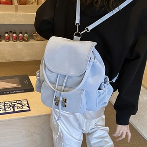 Detail of light blue backpack featuring a silver bow buckle and drawstring flap closure