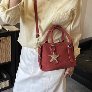 Detail of brick red mini pillow bag with silver star charm and adjustable strap