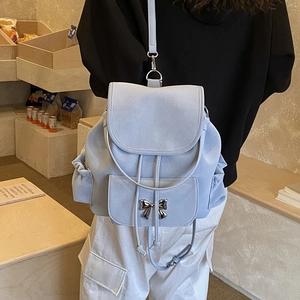 Detail of light blue suede backpack with silver bow buckle and drawstring closure