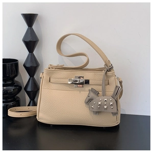 Detalle del bolso beige de piel granulada con cierre giratorio plateado y colgante de caballo