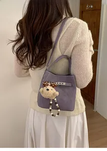 Detail of purple lychee grain leather bucket bag with silver lock and bear charm