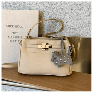 Detalle del bolso de cuero beige con cierre dorado y colgante de forma de caballo
