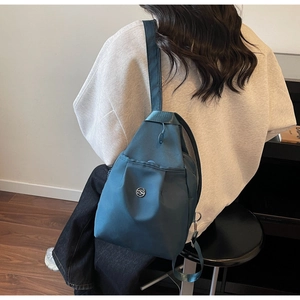 Detail des blaugrünen wasserdichten Nylon-Rucksacks mit Logo und strukturiertem Gurt