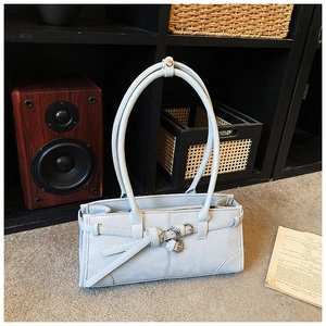 Detail of light grey-blue faux leather underarm bag with decorative straps and metal buckles