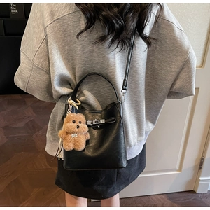 Detail of a vintage black leather bucket bag with silver twist lock and teddy bear charm