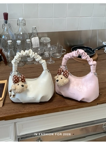 Close-up of pleated cloud-shaped handbags in white and pink with cute plush bear charms