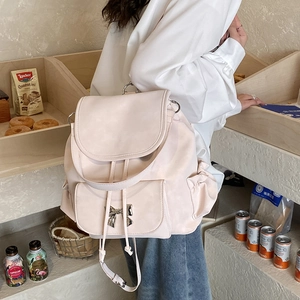 Detail of light pink backpack featuring a silver metal bow and drawstring closure