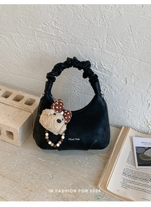 Detail of black crescent bag with scrunchie handle and cute plush bear charm