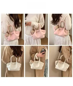 Detail of pink and cream tote bag with litchi texture, bear charm and strap