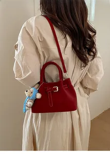 Detail of red pebbled leather bucket bag with gold buckle and cute bear charm pendant