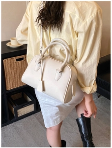 Vista posteriore di una modella che indossa la borsa Boston crema con tracolla regolabile