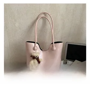 Detail showing the pink faux leather tote bag with a cute bear pendant in a lifestyle setting