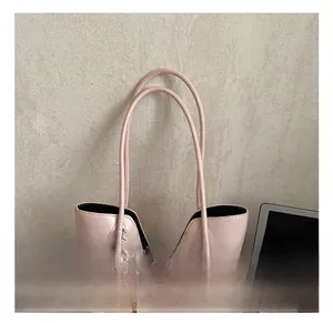 Detailed close-up of pink tote bag handles with a cute bear charm on office desk