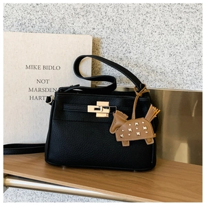 Detalle de bolso de cuero negro con grano litchi, cierre metálico y adorno de caballo