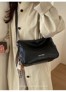 Detail of black tote bag with white stitching, brand logo, and baseball keychain pendant