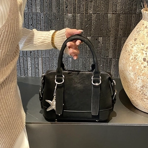 Detail of black suede Boston bag featuring double handles and star pendant charm