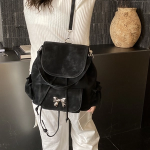Detail shot of black suede drawstring backpack featuring silver butterfly metal bow accent
