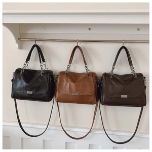 Detail view of quilted tote bags in three colors with metallic chain shoulder straps