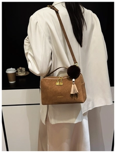 Detailansicht der braunen Wildledertasche mit goldenen Beschlägen und Quastenakzenten