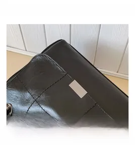 Macro detail of black quilted leather tote with silver rectangular metal accent