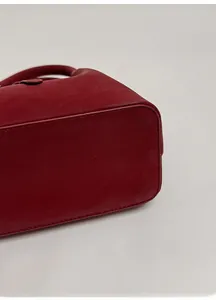 Detailed view of the dark red leather bucket bag featuring a sturdy shaped bottom base