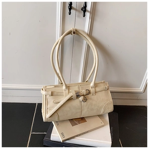 Detail view of cream vintage underarm bag with decorative straps on a marble surface