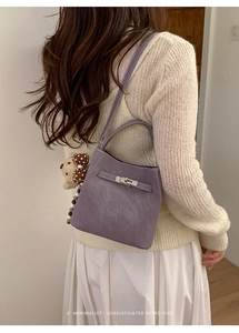 Detail of purple bucket bag with metal twist lock and cute teddy bear charm on model