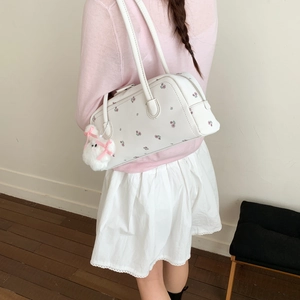 Borsa a spalla bianca a fiori con ciondolo a coniglio su un outfit rosa tenue