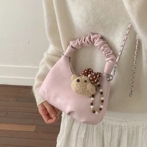 Pink ruched shoulder bag with plush bear charm and metallic chain shown on a model