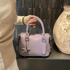 Detail of lilac Boston bag with round handles and a silver starfish charm accessory