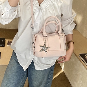 Close-up of pink leather Boston bag featuring star pendant and metallic hardware details