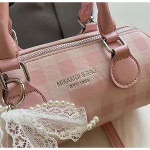 Détail du sac polochon à carreaux roses avec logo argenté et nœud en dentelle perle