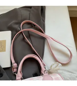 Détail du sac cylindre à carreaux roses avec bandoulière et accessoire en perles